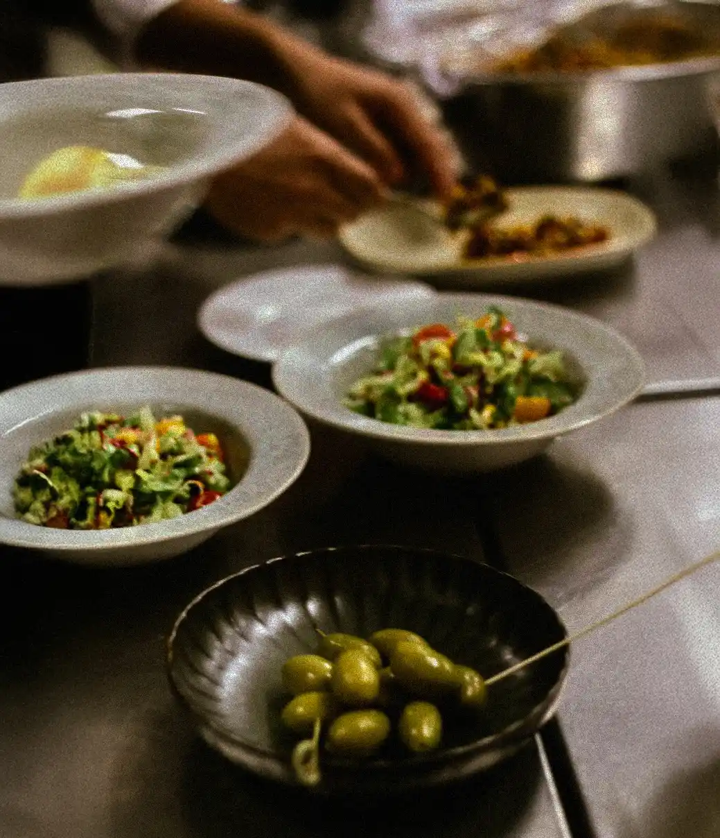 Frische Salate mit Oliven werden in der Küche angerichtet und für den Service vorbereitet.